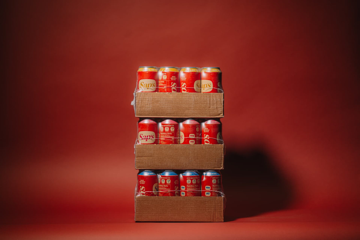 Stack of Sap's cans in cardboard boxes on a red background