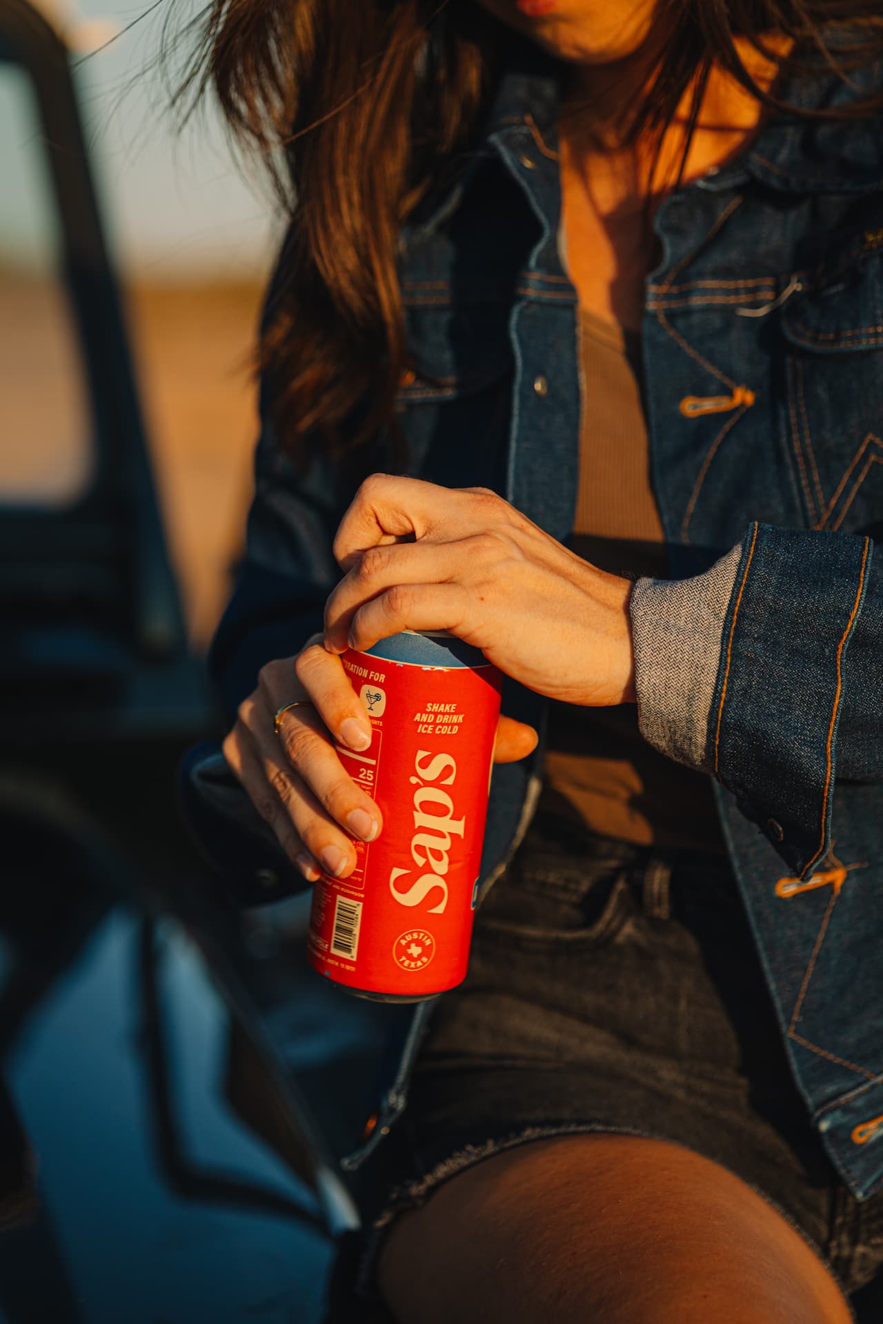 Person holding a red can of Saps against a blurred background